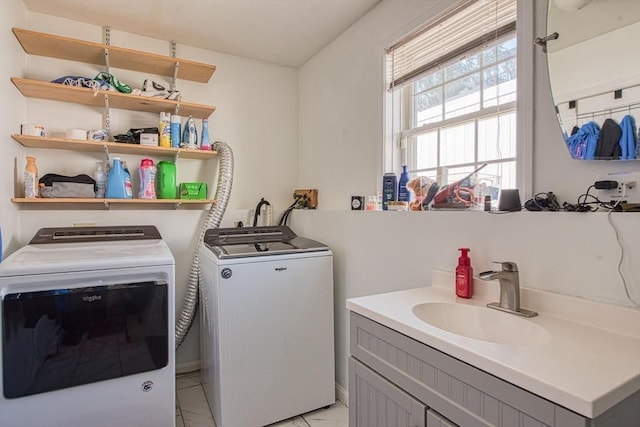 clothes washing area with washer and clothes dryer, cabinet space, and a sink