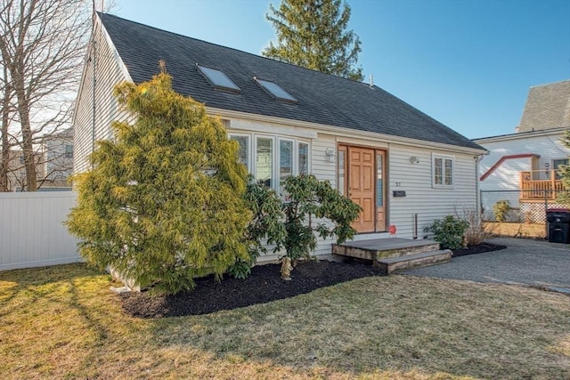 view of front of property with roof with shingles, a front yard, and fence