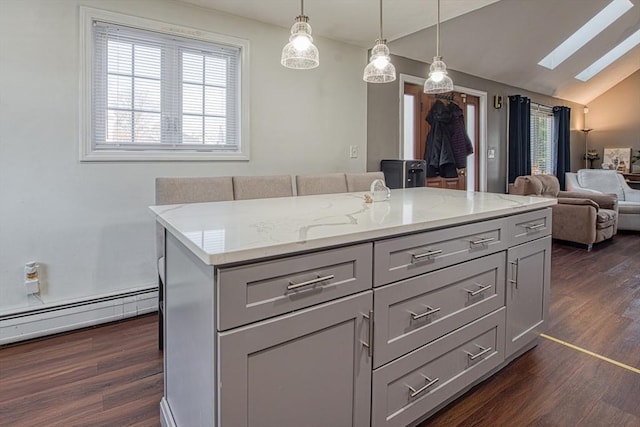 kitchen with dark wood-type flooring, gray cabinetry, a baseboard heating unit, vaulted ceiling with skylight, and light stone countertops