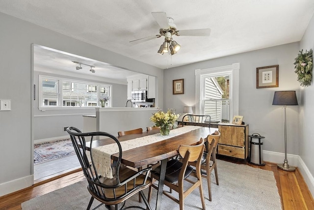 dining area featuring light wood-style floors, a ceiling fan, and baseboards
