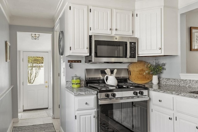 kitchen featuring appliances with stainless steel finishes, light tile patterned floors, light stone counters, baseboards, and white cabinetry