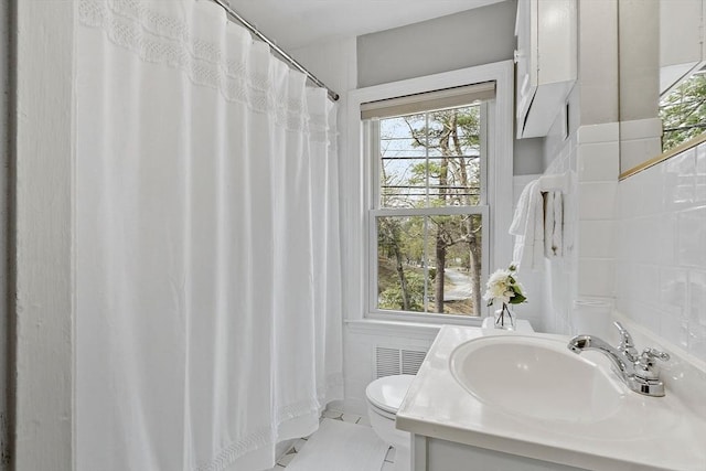 bathroom featuring plenty of natural light, toilet, and tile walls
