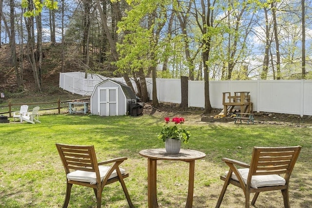 view of yard featuring a fenced backyard, a shed, and an outbuilding