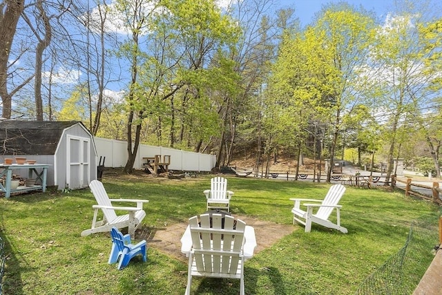 view of yard with a fenced backyard, a storage unit, and an outbuilding