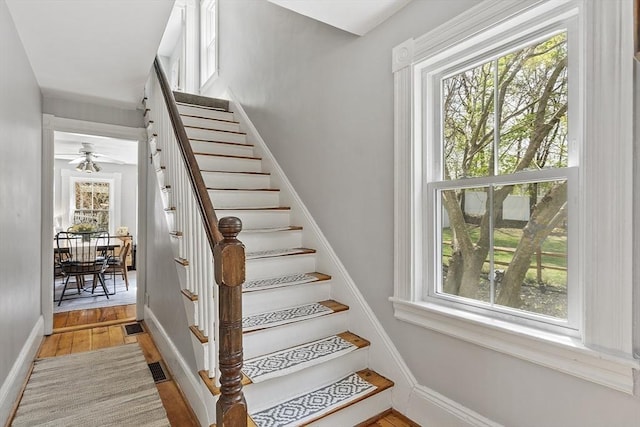 stairway featuring baseboards, ceiling fan, and wood finished floors