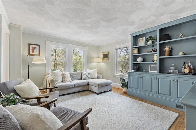 living room with crown molding, plenty of natural light, and light wood-style floors