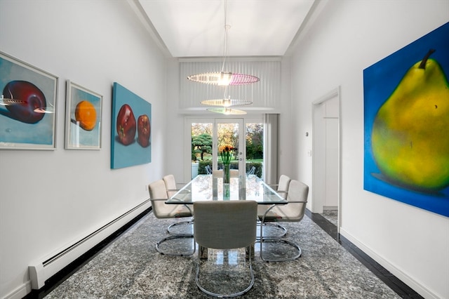 dining room featuring a towering ceiling, a baseboard radiator, and an inviting chandelier