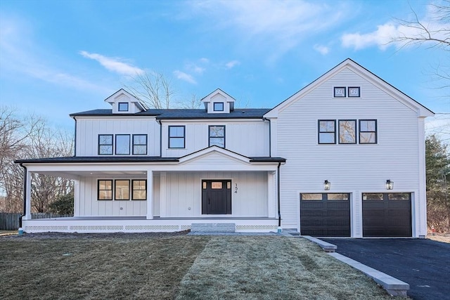 modern farmhouse with a front lawn, covered porch, and a garage