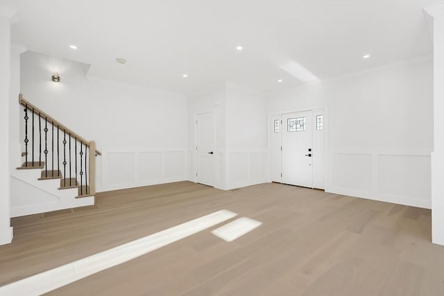 unfurnished living room featuring crown molding and light wood-type flooring