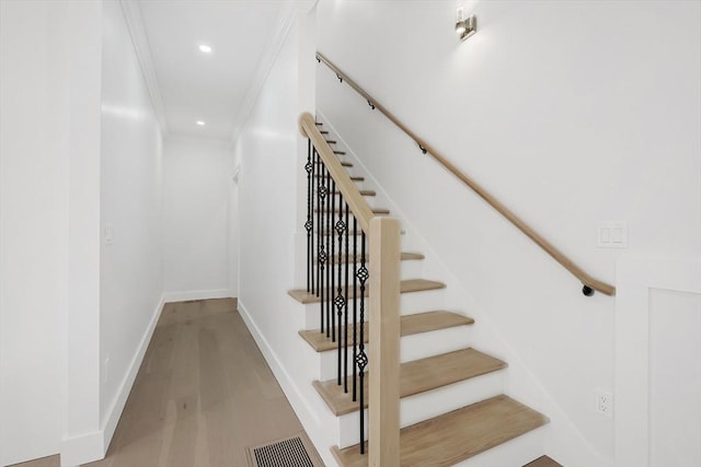 stairs featuring crown molding and hardwood / wood-style floors