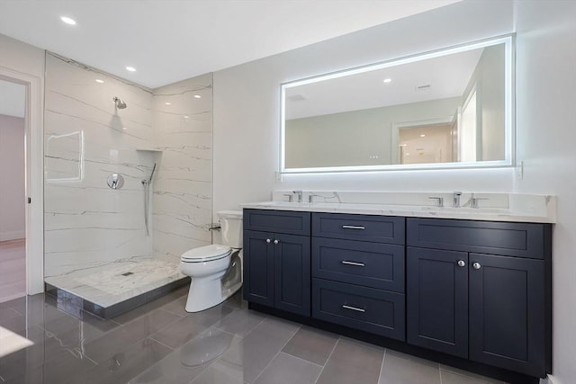 bathroom with tile patterned flooring, a tile shower, vanity, and toilet