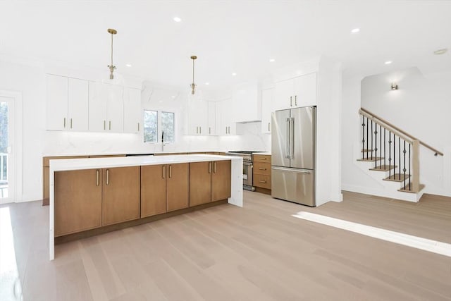 kitchen featuring custom exhaust hood, high quality appliances, a spacious island, decorative light fixtures, and white cabinetry