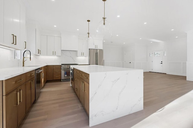 kitchen with custom exhaust hood, stainless steel appliances, decorative light fixtures, a center island, and white cabinetry