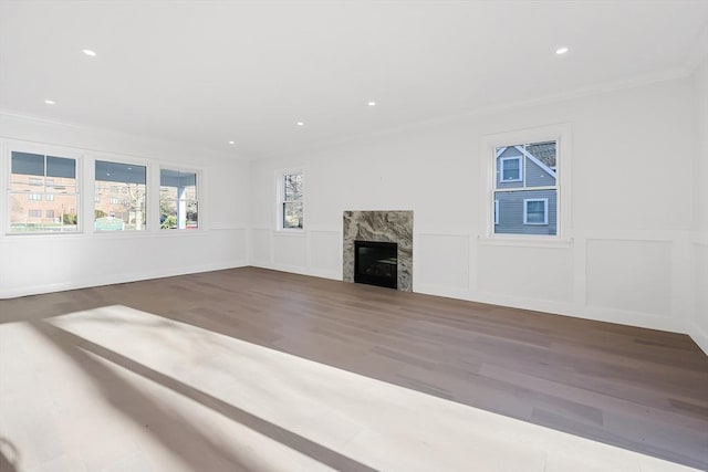 unfurnished living room with crown molding, a premium fireplace, and hardwood / wood-style flooring