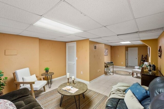 tiled living area featuring baseboards, visible vents, and a drop ceiling