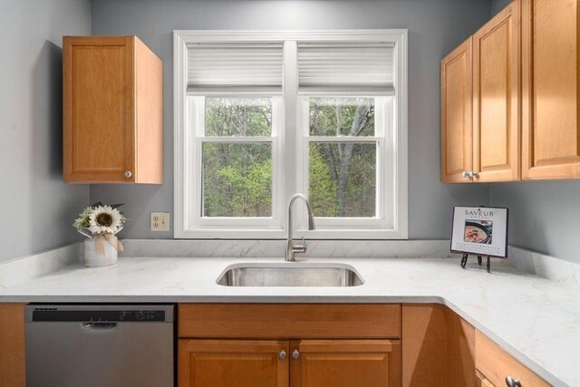 kitchen featuring stainless steel dishwasher, light stone countertops, and a sink