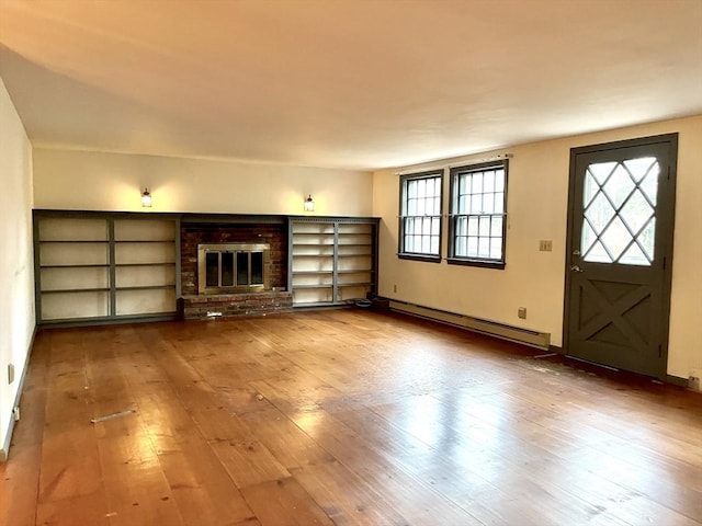 unfurnished living room with wood-type flooring, baseboard heating, and a brick fireplace