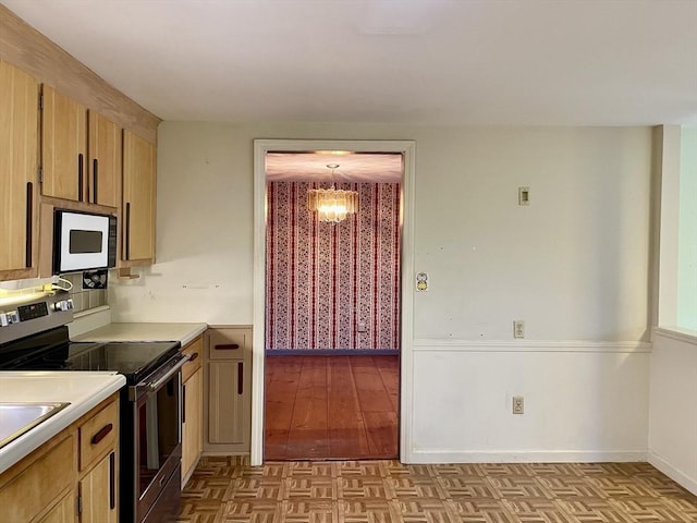 kitchen with a chandelier, light brown cabinets, stainless steel range with electric cooktop, and hanging light fixtures