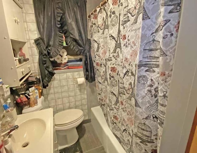 full bathroom with toilet, sink, tile walls, and shower / bath combo