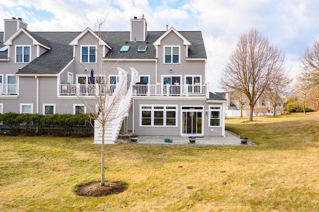 rear view of house with a balcony, a yard, and a patio