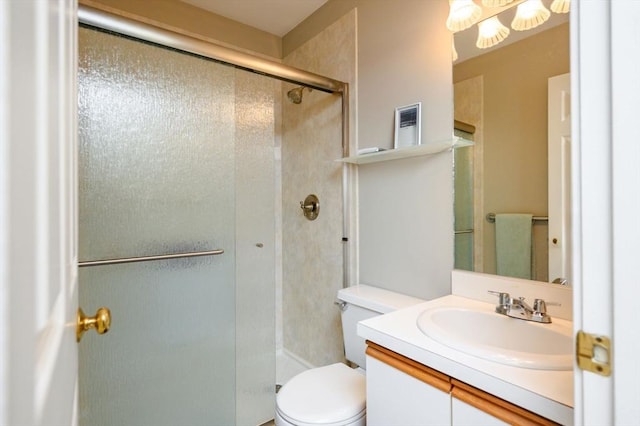 bathroom featuring a shower with door, vanity, and toilet