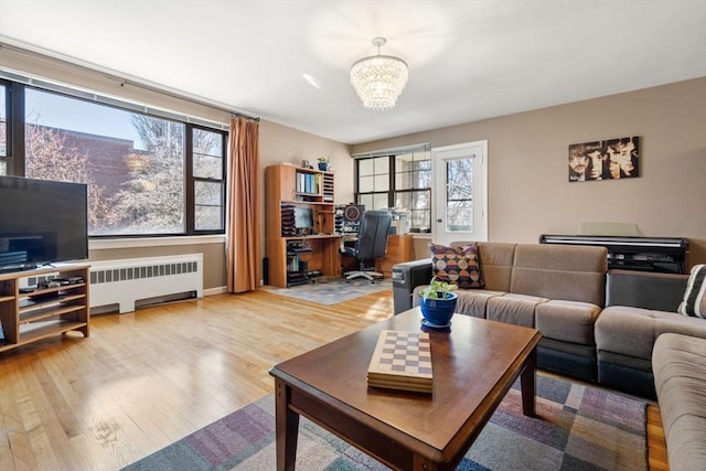 living room with radiator heating unit, a notable chandelier, and light hardwood / wood-style flooring