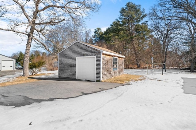 snow covered garage featuring aphalt driveway and a detached garage