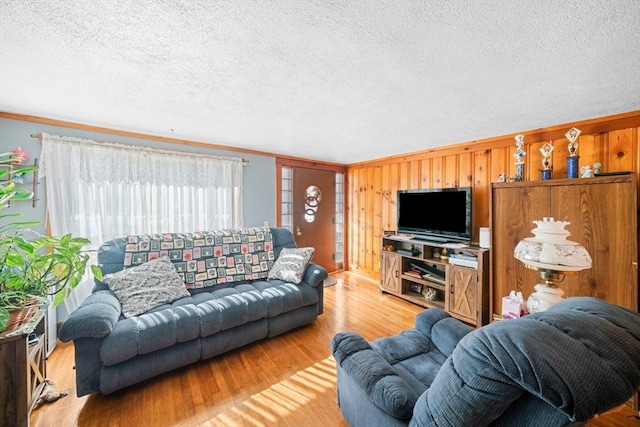 living room featuring a textured ceiling, wood walls, and wood finished floors