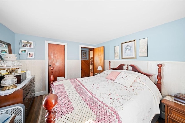 bedroom with dark wood-type flooring, wainscoting, and heating unit