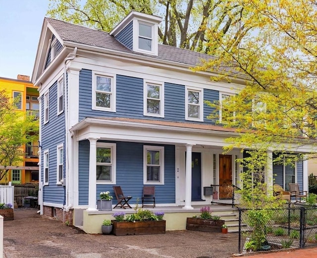 view of front of property featuring a porch, fence, and a shingled roof