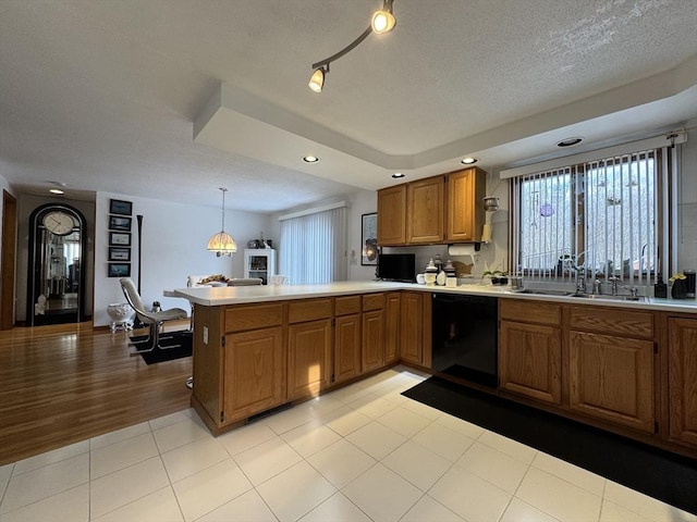 kitchen with black dishwasher, light tile patterned floors, sink, kitchen peninsula, and pendant lighting