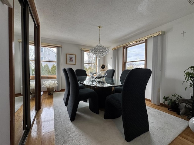 dining space featuring light hardwood / wood-style floors, a textured ceiling, and an inviting chandelier