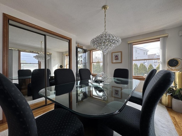 dining area featuring a textured ceiling, an inviting chandelier, and light hardwood / wood-style flooring