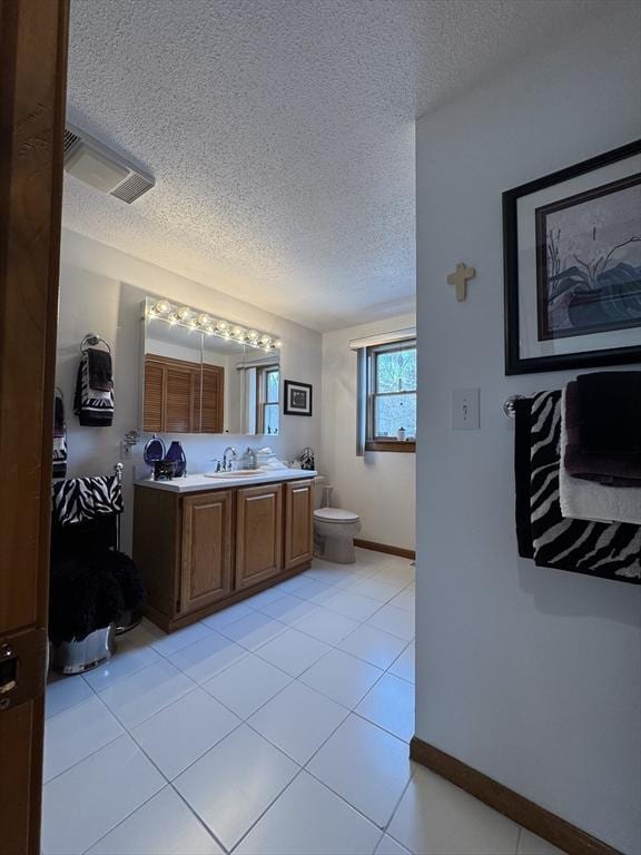 bathroom featuring vanity, toilet, tile patterned floors, and a textured ceiling