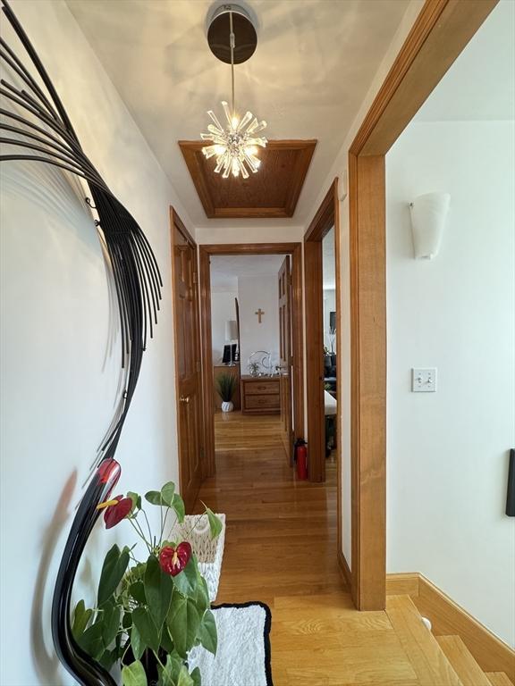 hallway with light hardwood / wood-style flooring and an inviting chandelier