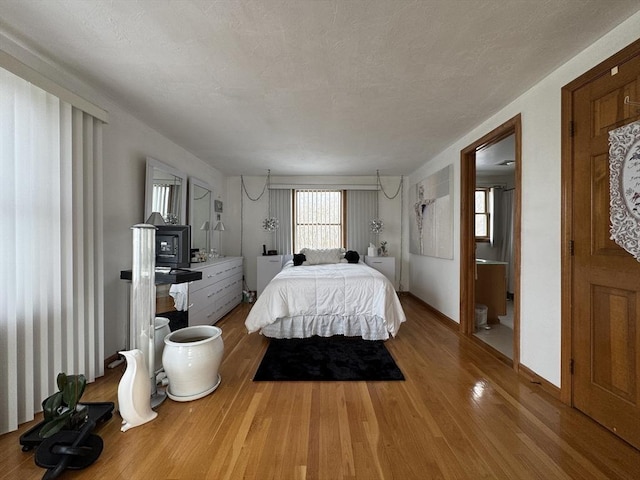 bedroom with hardwood / wood-style flooring, a textured ceiling, and an AC wall unit