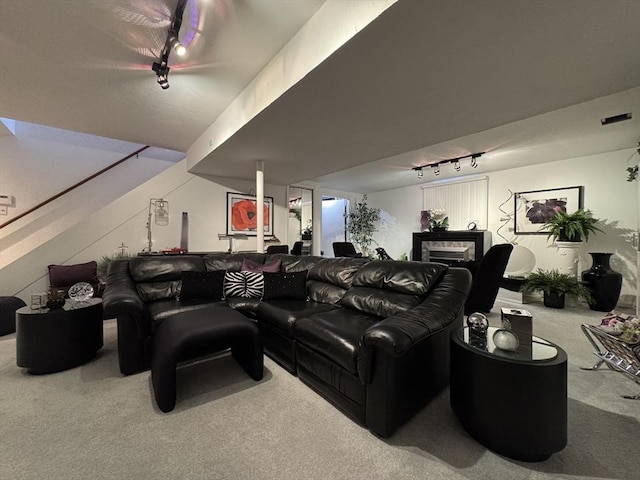 carpeted home theater featuring track lighting and a tiled fireplace