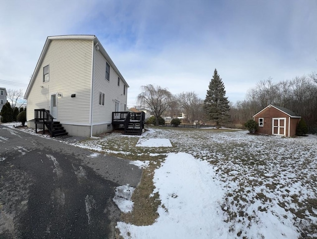 view of snow covered exterior featuring a deck and a shed