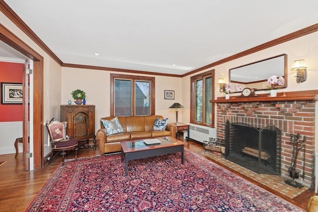 living room featuring radiator, a brick fireplace, crown molding, and wood finished floors