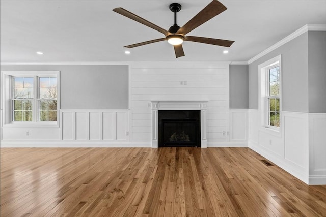312 Old Westport, Dartmouth, MA 02747 - unfurnished living room featuring a ceiling fan, crown molding, light wood-style flooring, a wainscoted wall, and a fireplace