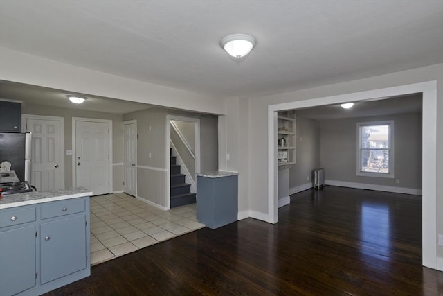 kitchen featuring hardwood / wood-style floors, blue cabinets, radiator heating unit, and stainless steel refrigerator