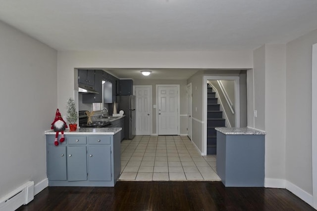 kitchen with sink, stainless steel appliances, a baseboard heating unit, kitchen peninsula, and light hardwood / wood-style floors