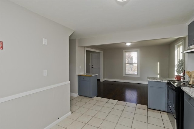 kitchen with electric stove, light stone countertops, and light hardwood / wood-style floors