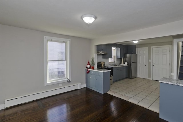 kitchen with appliances with stainless steel finishes, light wood-type flooring, a baseboard radiator, and sink