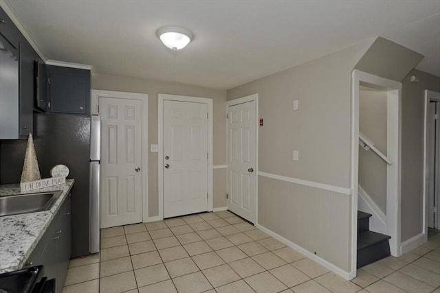 kitchen with light stone countertops, range, sink, and light tile patterned flooring