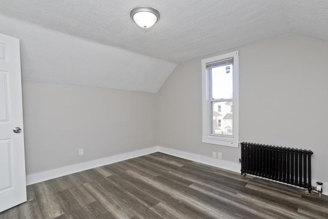 additional living space featuring a textured ceiling, radiator heating unit, and dark wood-type flooring