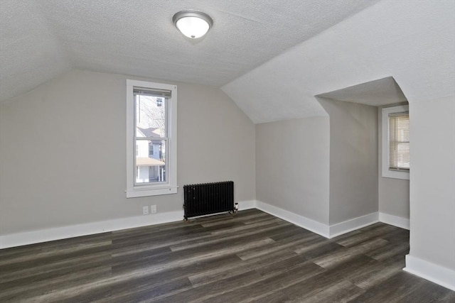 bonus room with dark hardwood / wood-style floors, radiator heating unit, a textured ceiling, and lofted ceiling