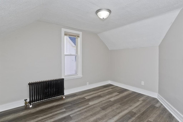 bonus room featuring lofted ceiling, dark hardwood / wood-style flooring, radiator heating unit, and a textured ceiling