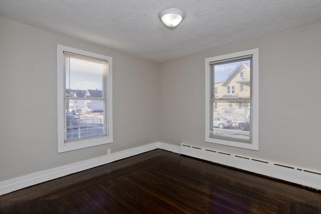 spare room with a textured ceiling, a healthy amount of sunlight, a baseboard radiator, and wood-type flooring