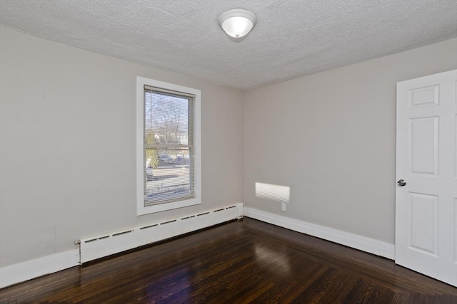 spare room with dark hardwood / wood-style floors, a textured ceiling, and a baseboard radiator